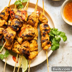 Top-down view of chicken satay with peanut sauce and red chilli sauce