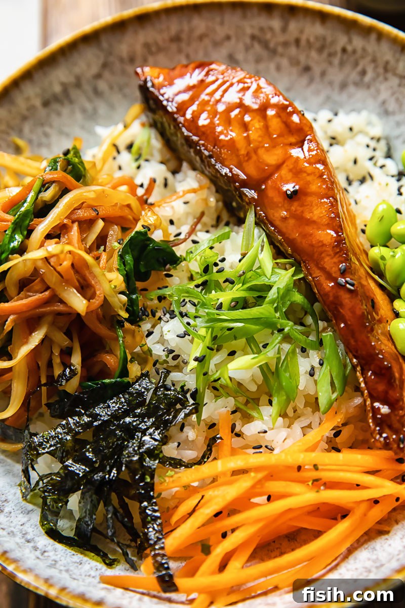 close up of rice bowl topped with salmon, stir fried vegetables and other toppings