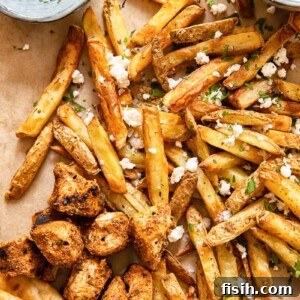 top down view of fries topped with feta, grilled chicken bites, pita and yogourt dip