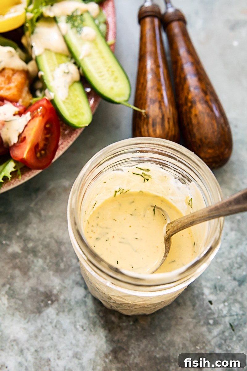 Artisan Salmon Cobb with Zesty Lemon-Dill Dressing 4 A charming close-up of the homemade lemon dill dressing, presented in a mason jar, showcasing its creamy texture and fresh herbs, ready to drizzle over the salad.