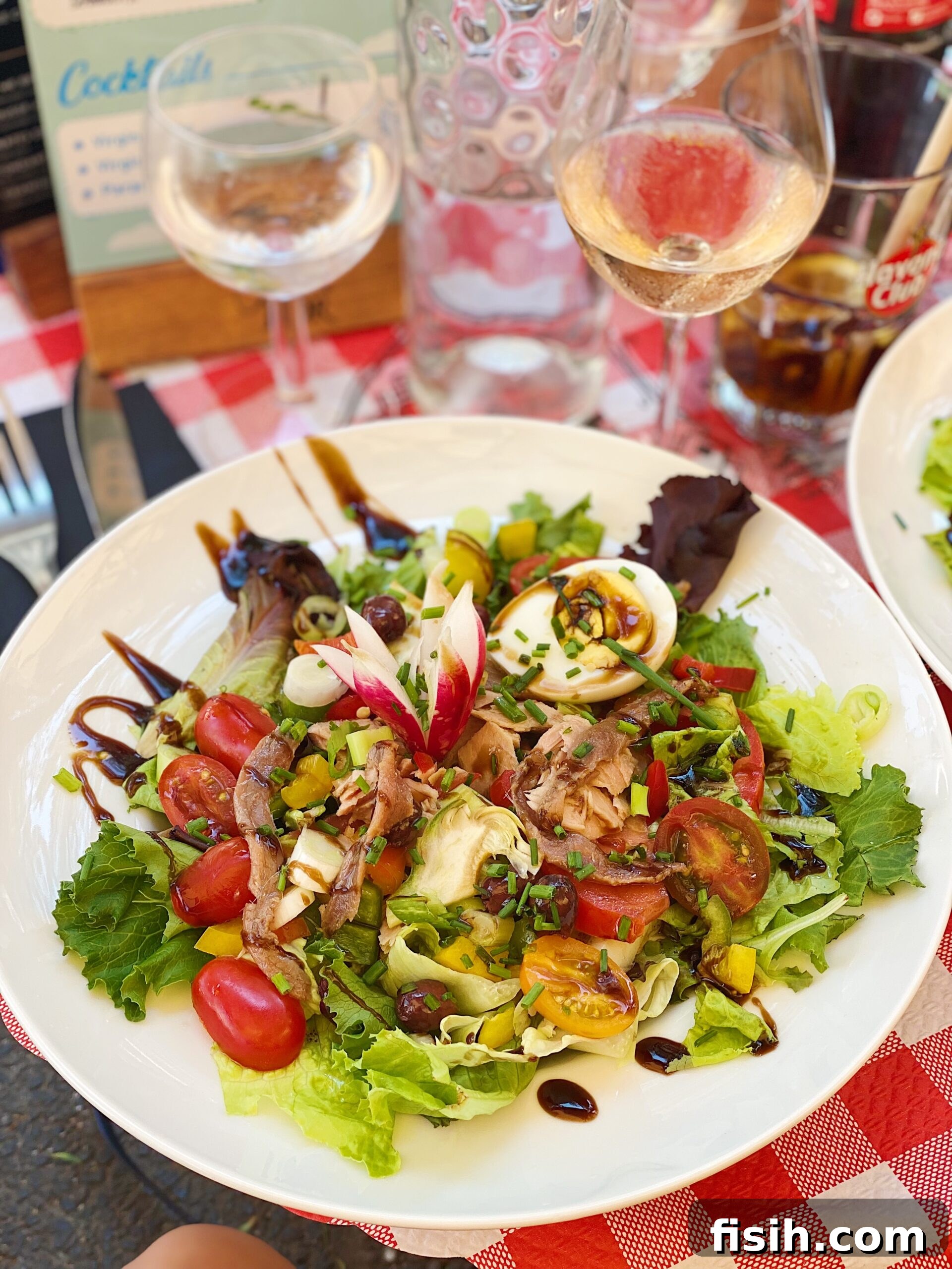A vibrant and artfully arranged Salad Nicoise featuring fresh greens, various vegetables, tuna, and eggs, highlighting its diverse ingredients.