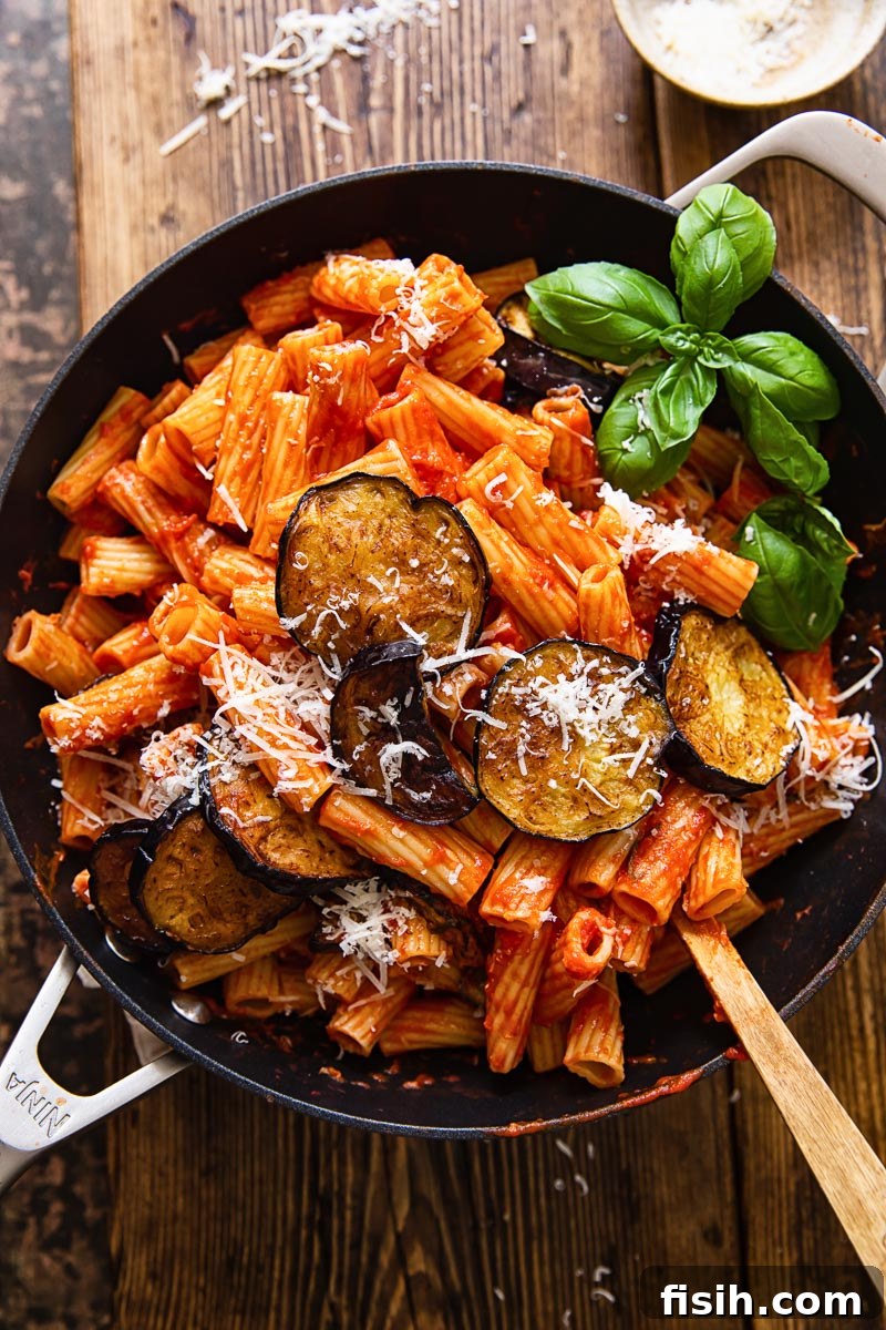 Sicilian Eggplant Pasta Alla Norma 2 top down view of rigatoni with tomato sauce, topped with sliced of fried eggplant and grated Parmesan