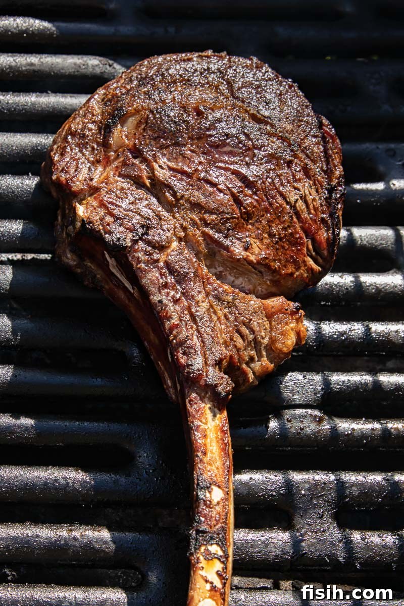 cooked tomahawk steak searing on a hot grill, showing a beautiful crust