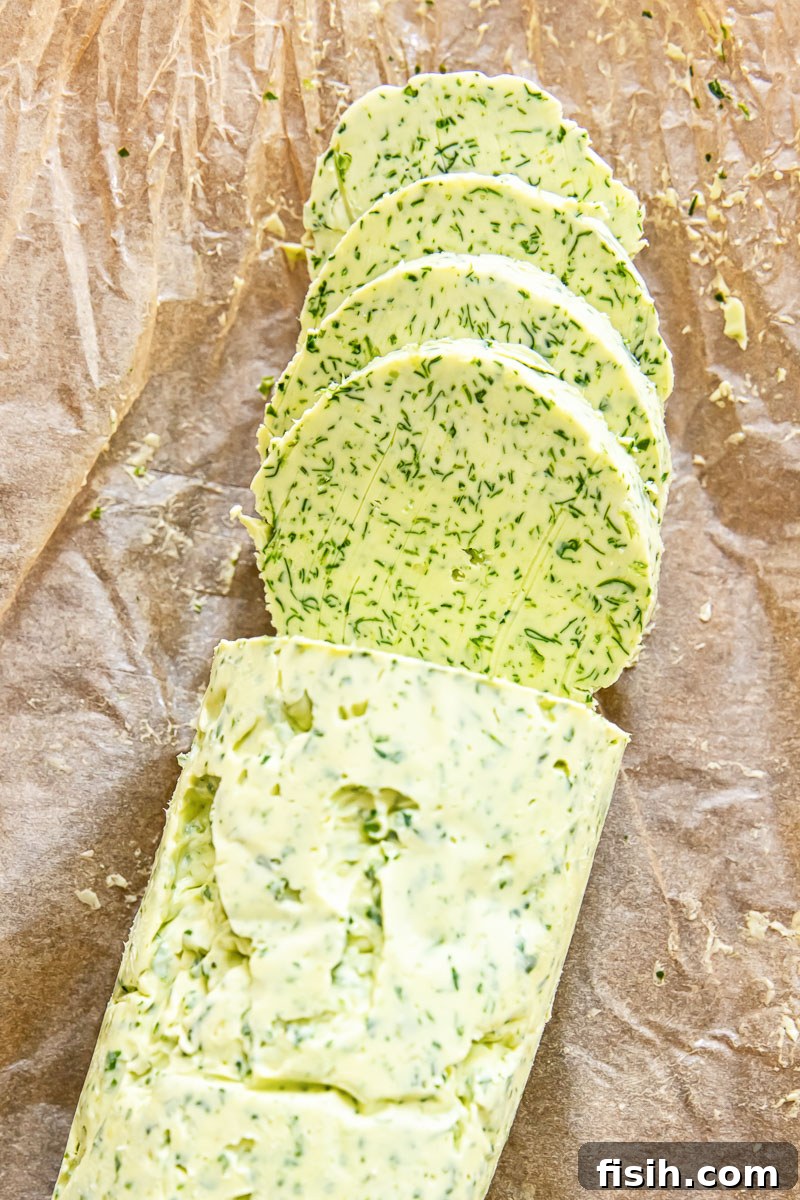 Sliced block of vibrant green garlic herb butter on a cutting board, ready to serve.