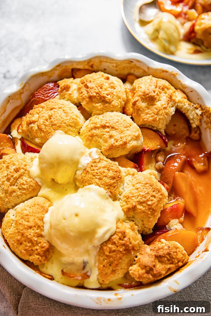 Golden-brown maple peach cobbler in a rustic round pan, ready to be served.