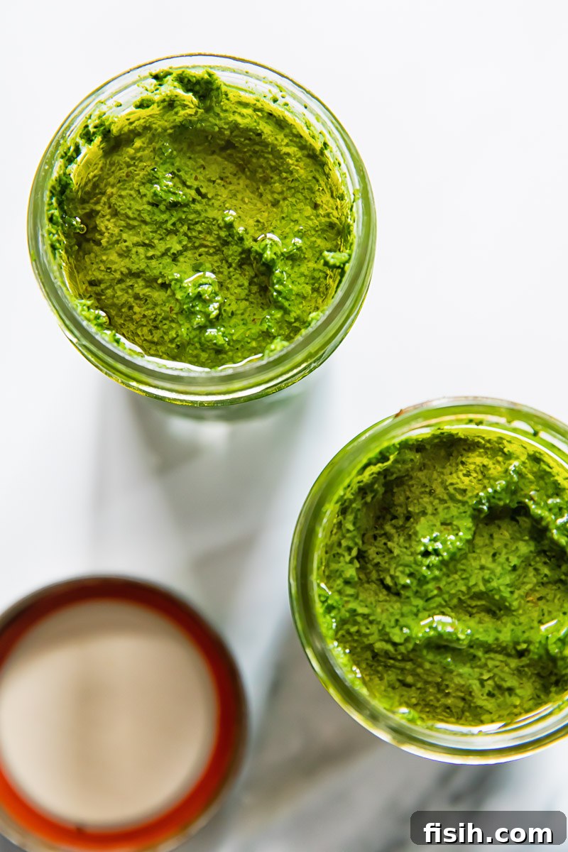 A top-down perspective of two glass jars filled with homemade Tuscan kale pesto, neatly sealed and ready for storage.