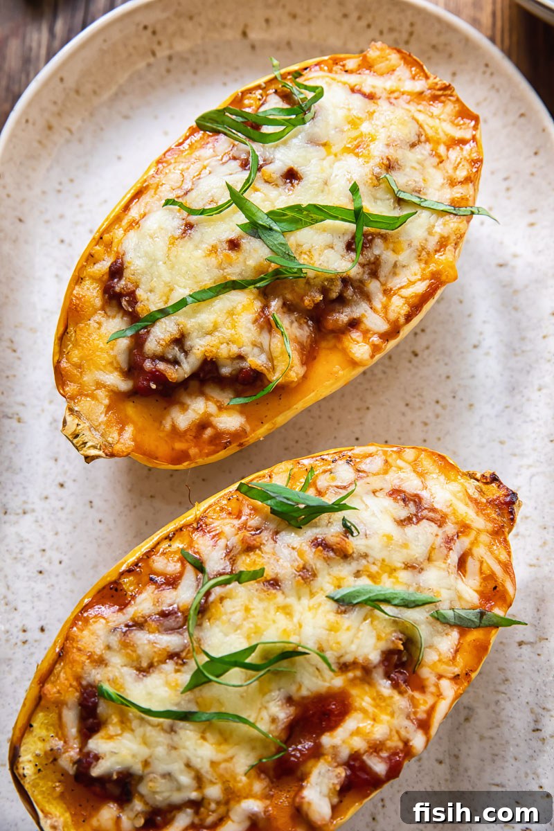 Two golden-brown stuffed spaghetti squash halves, fresh out of the oven, arranged on a serving platter with melted cheese.