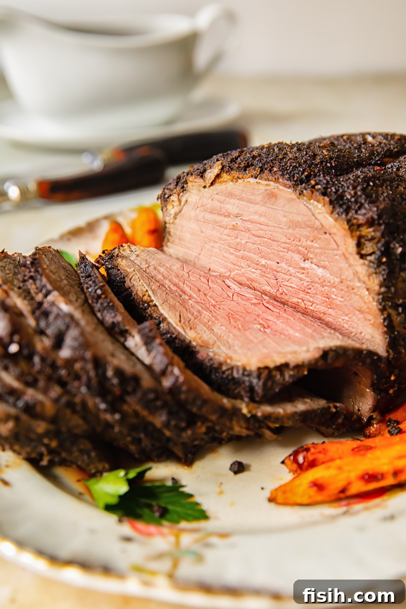 A side view of thinly sliced, medium-rare roast beef, showcasing its juicy interior, beautifully arranged on a serving platter.