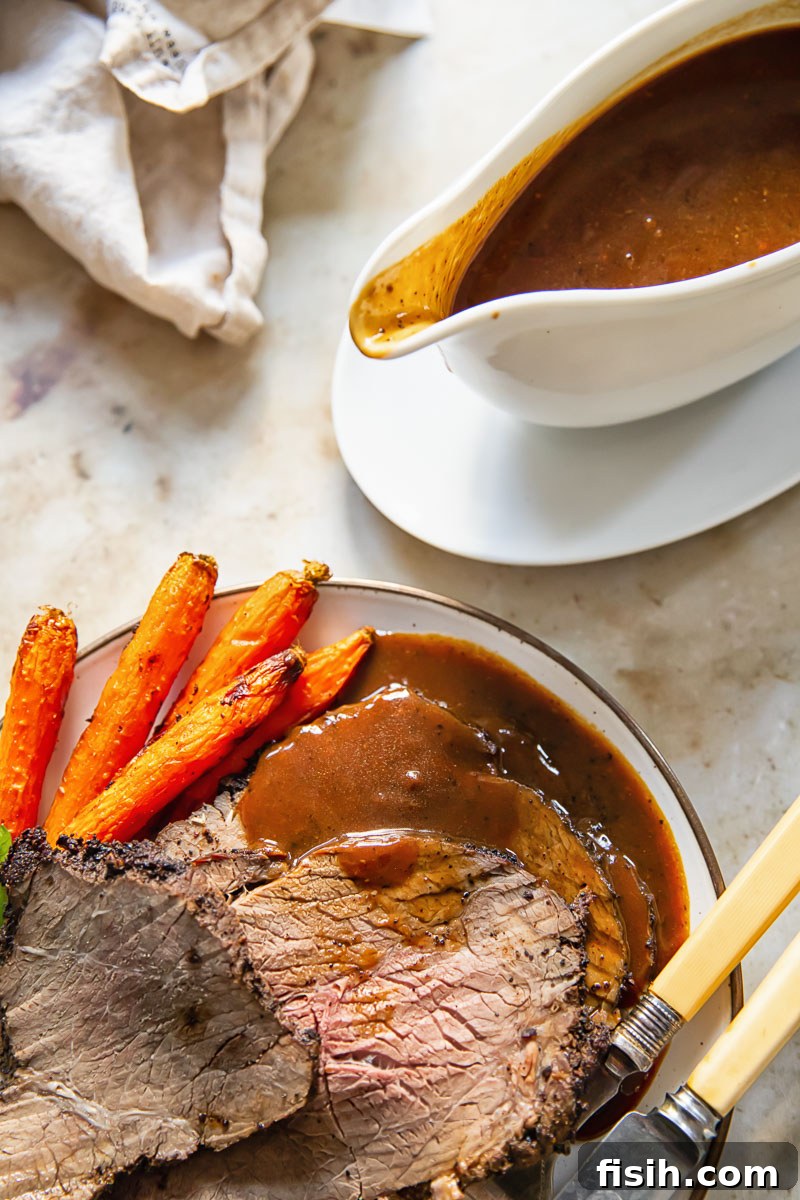 A top-down view of beautifully sliced roast beef, served on a plate with rich gravy and roasted carrots, with a gravy boat nearby, highlighting a complete and inviting meal.