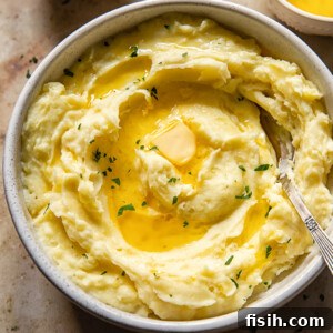 Top down view of mashed potatoes drizzled with melted butter and chopped parsley in a bowl