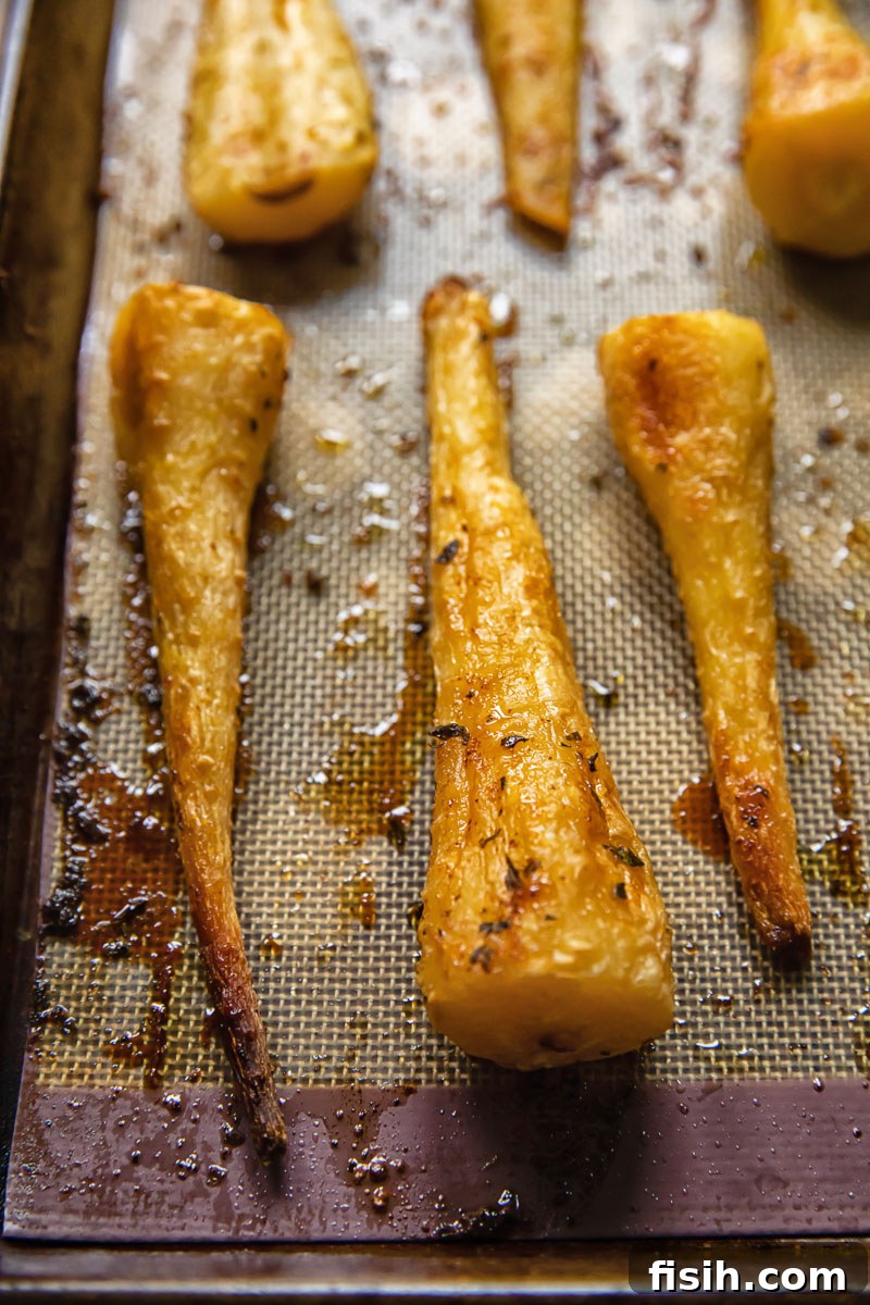 Caramelized Honey Garlic Parsnips 3 Close-up view of honey garlic roasted parsnips on a baking tray, showing their golden crust and tender appearance.
