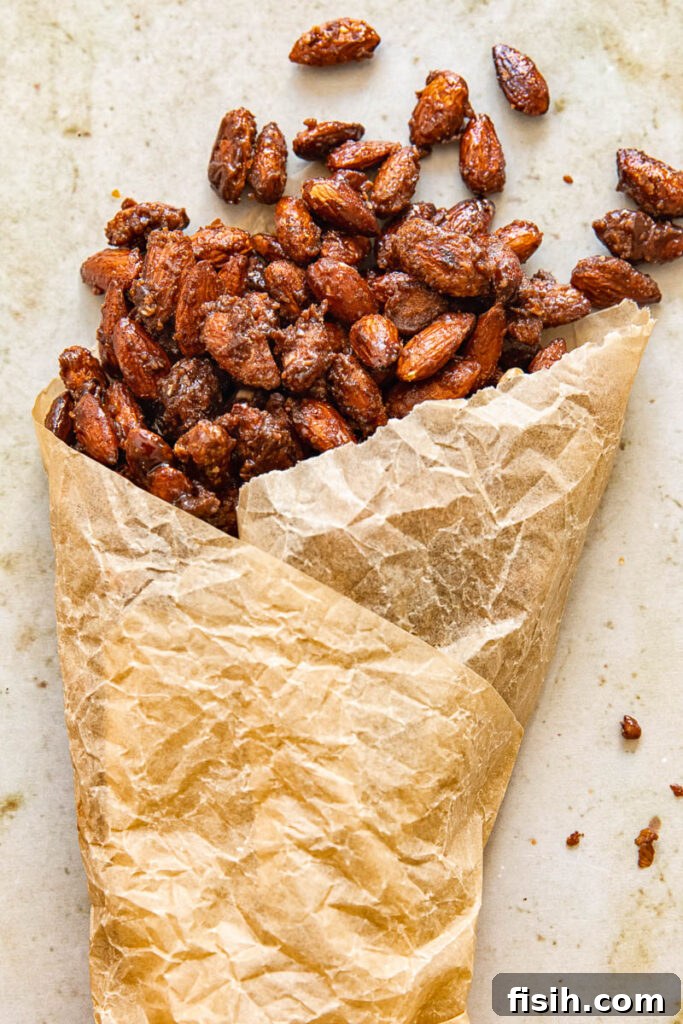 Candied almonds elegantly spilling from a parchment paper cone, showcasing their golden crunch, ready to be served or gifted.