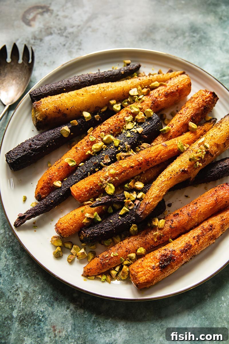 Golden-Roasted Rainbow Carrots with Toasted Pistachios 4 top down view of cooked rainbow carrots with chopped pistachios on a white platter, ready to serve