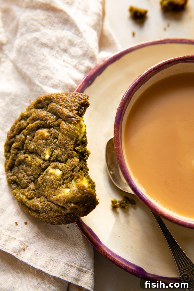 Matcha Bliss White Chocolate Cookies 3 top down view of a cup of tea on a saucer and a half eaten cookie