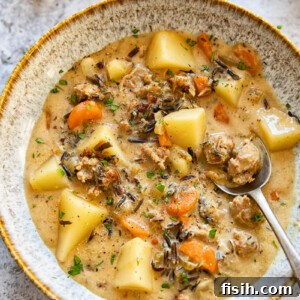 A bowl of potato and sausage chowder with a spoon, highlighting the creamy texture and hearty chunks.