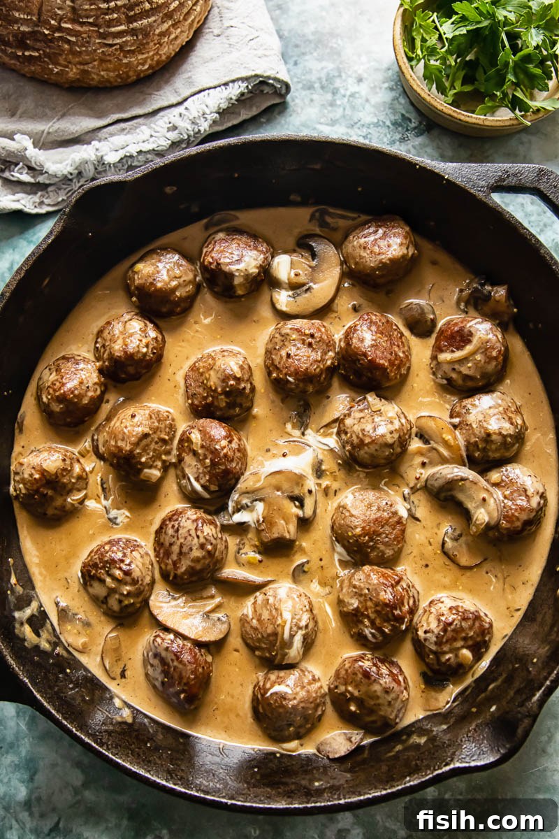 meatballs stroganoff in a skillet on blue background