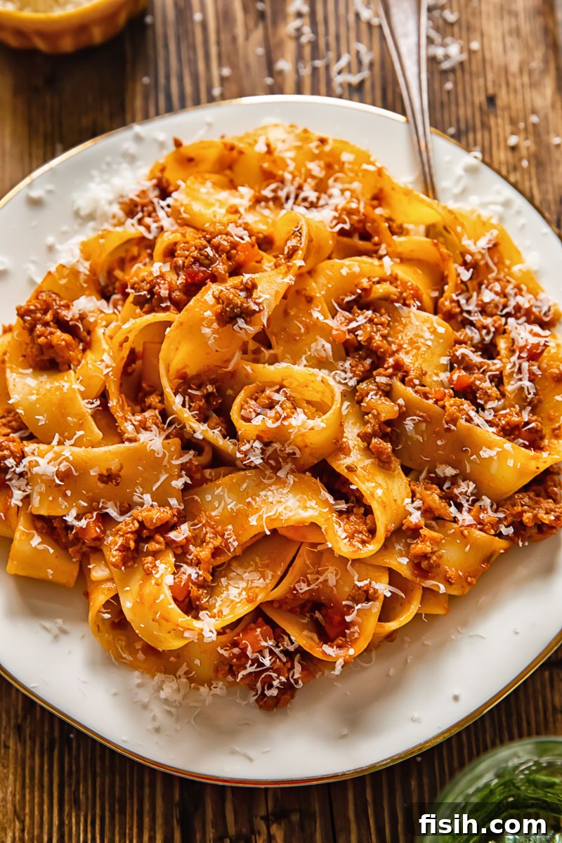 A serving of Tuscan ragu with pasta on a white plate, ready to be enjoyed with a fork