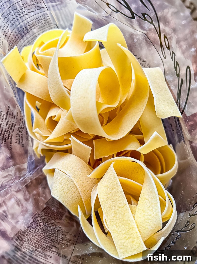 Dried pappardelle pasta neatly arranged in a clear plastic bag, ready for cooking