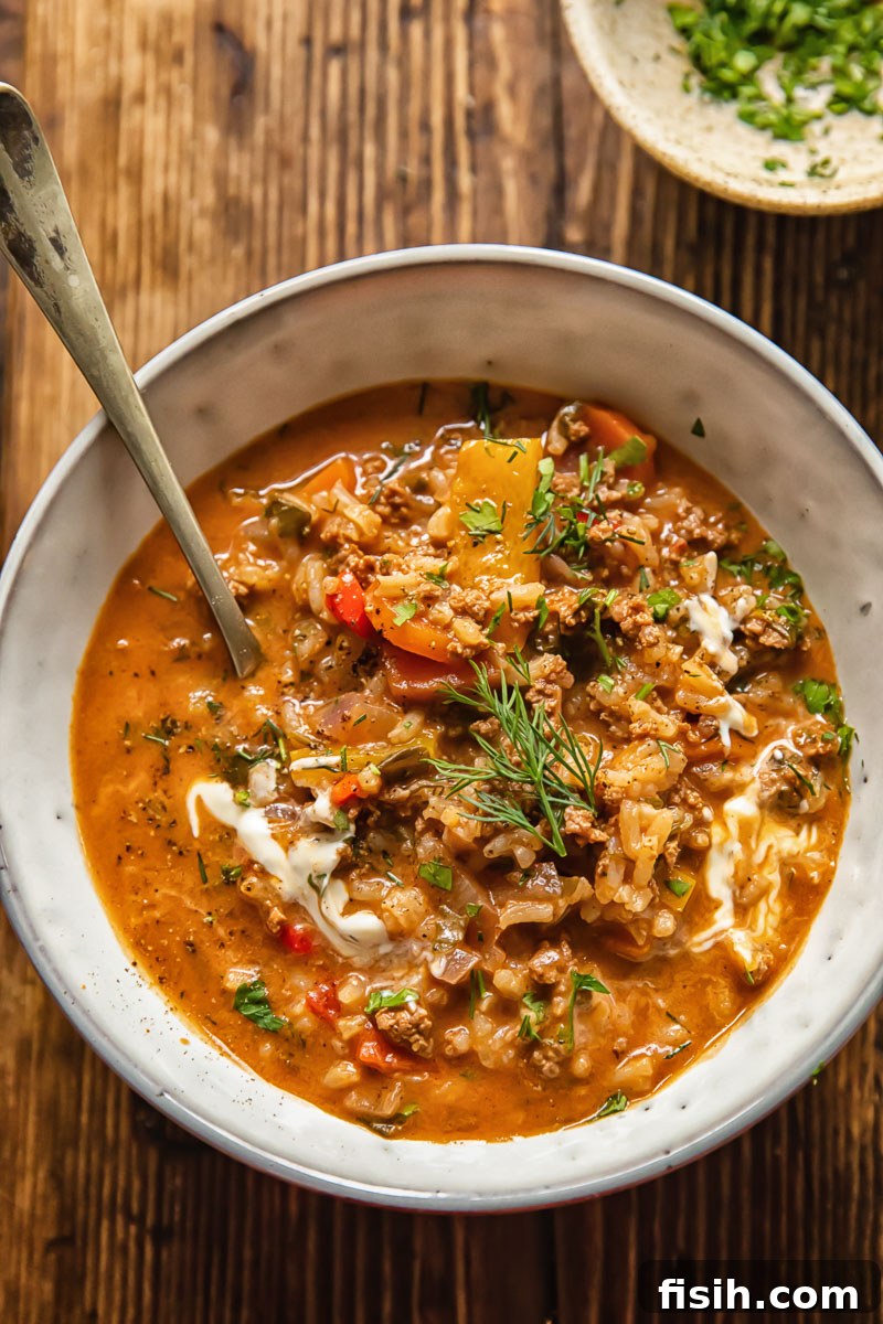 A bowl of unstuffed pepper soup, served with a spoon and garnished, ready to be enjoyed.