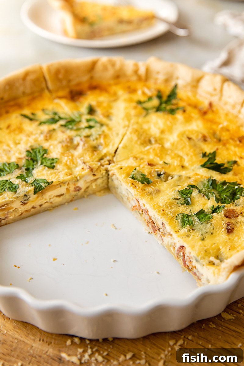 Gourmet Bacon Stilton Caramelised Onion Quiche 3 Side view of a deep-dish quiche with several slices already removed, revealing the layers of filling and flaky crust.