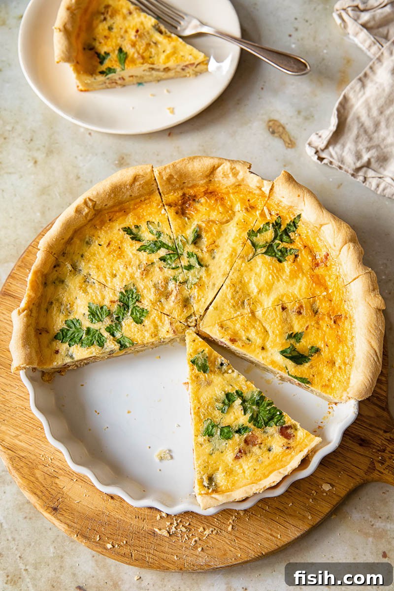 Gourmet Bacon Stilton Caramelised Onion Quiche 4 Top down view of a whole quiche, with one slice meticulously removed, highlighting the perfect crust and layered filling.