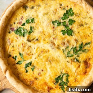 Gourmet Bacon Stilton Caramelised Onion Quiche 7 Top down view of a Bacon, Stilton, and Caramelised Onion Quiche on a round wooden cutting board.