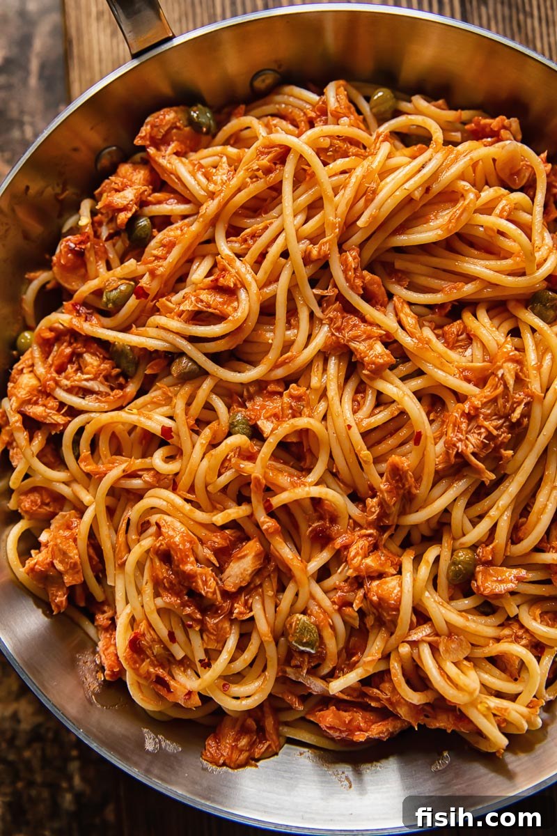Tangy Tuna Pasta in Minutes 5 Close-up of freshly cooked spaghetti with flaked tuna in a vibrant red sauce, ready to be served.