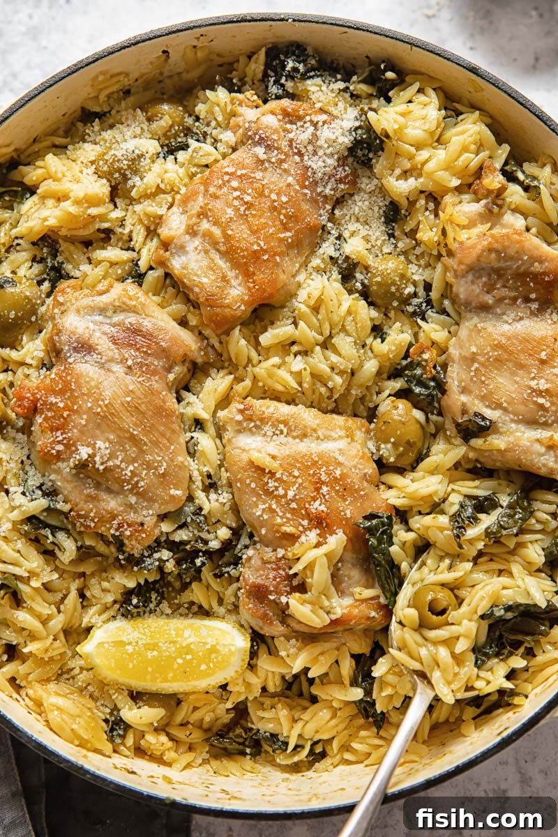 basil pesto orzo with chicken thighs and lemon wedges in a cast iron pan