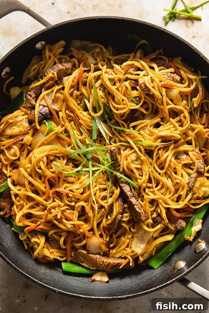 yakisoba noodles, beef, and vegetables cooking in a wok