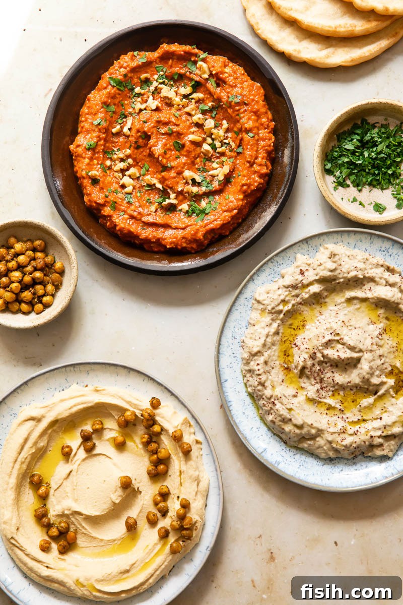Silky Hummus with Golden Za'atar Chickpea Crunch 5 top down view of Middle Eastern spreads on plate, roasted chickpeas in a bowl, chopped parsley in a bowl