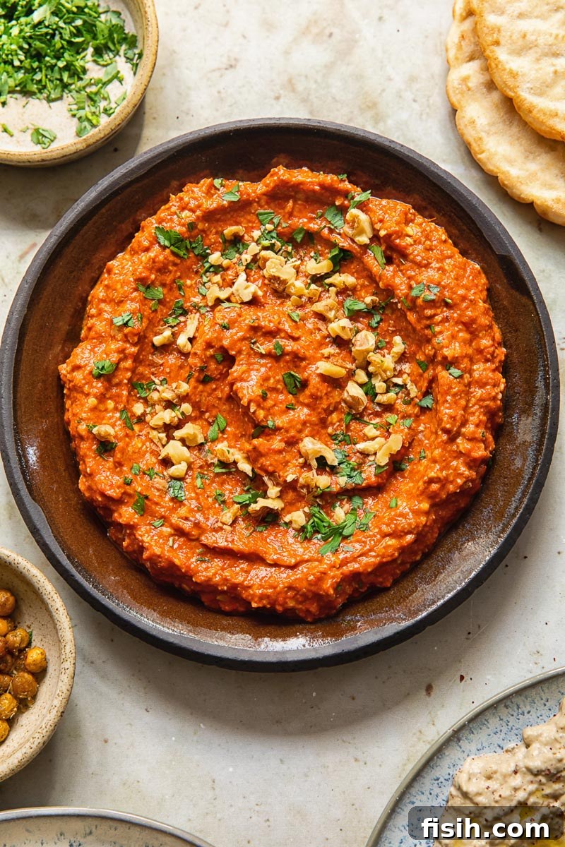 Top down view of Muhammara dip in bowl sprinkled with walnuts and parsley