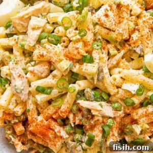 Close up of tuna macaroni salad with peas and green onion in a bowl.