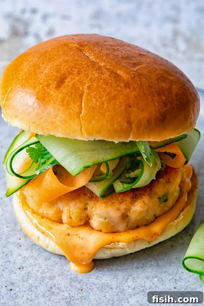 Zesty Salmon Burgers Topped with Spicy Carrot-Cucumber Slaw 3 Top-down view of a salmon burger generously topped with carrot cucumber slaw