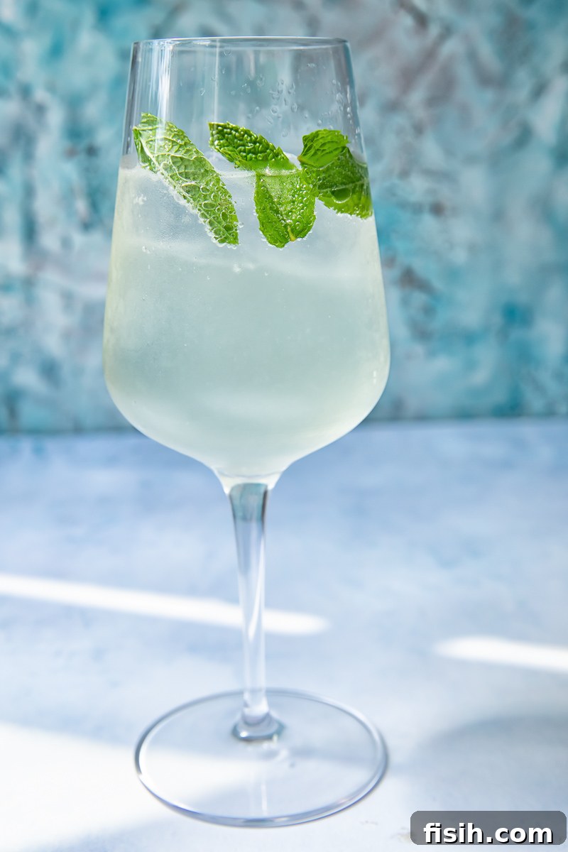 Verdant Spritz 2 A vibrant Mojito Spritz in a tall glass, garnished with fresh mint leaves and a lime wedge, sparkling under the sun.