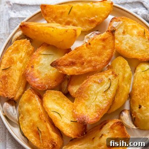 Top down view of golden roast potatoes on a plate.