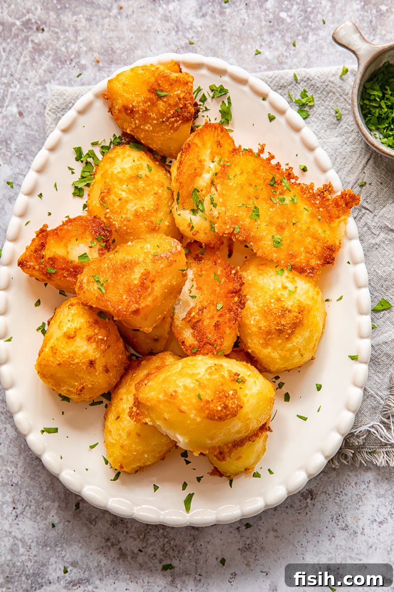 Top down view of freshly roasted Parmesan crusted potatoes garnished with vibrant fresh chives on an elegant serving platter.