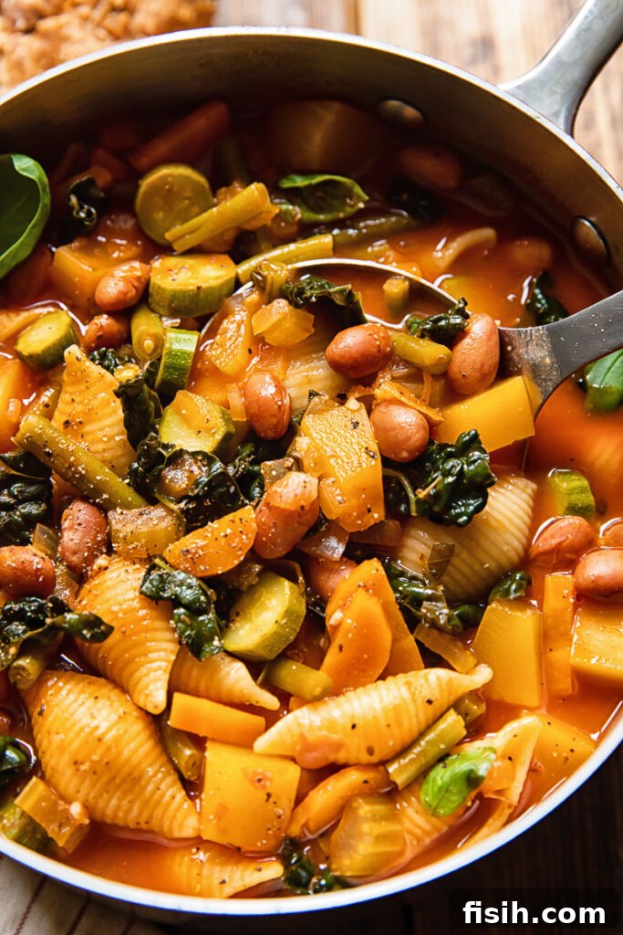 A large soup pot filled with minestrone soup, with a ladle resting inside, ready to be served.