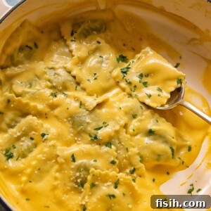 spoon holding a parcel of ravioli in pot of pasta in squash sauce