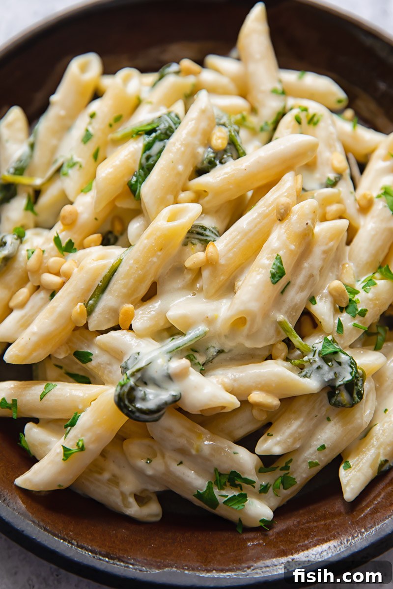 A vibrant plate of goat cheese pasta, elegantly garnished with fresh parsley and crunchy pine nuts, ready to be enjoyed.