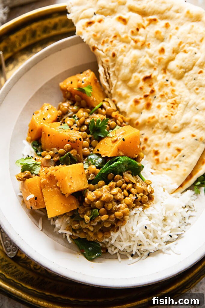 A serving of vegan coconut lentil curry with butternut squash in a rustic bowl, garnished with fresh cilantro.