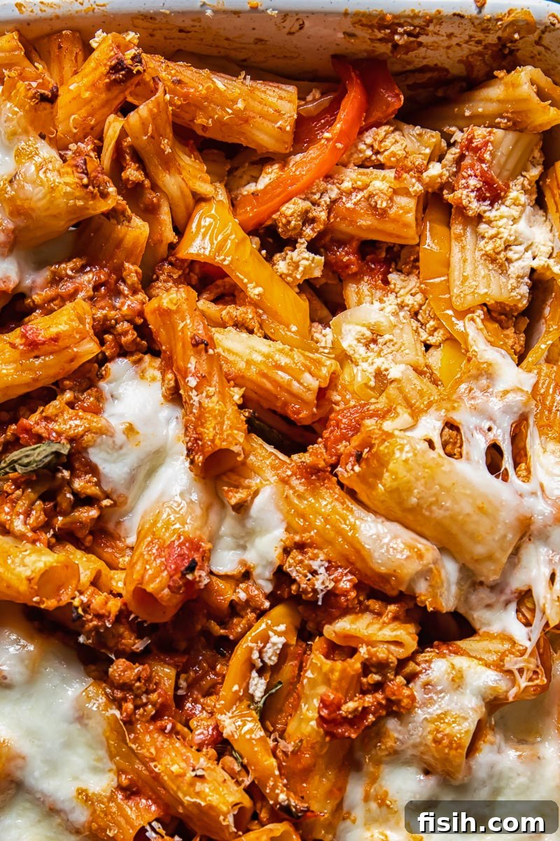 Close up shot of pasta in a baking dish with tomato sauce, fennel seeds and melted cheese