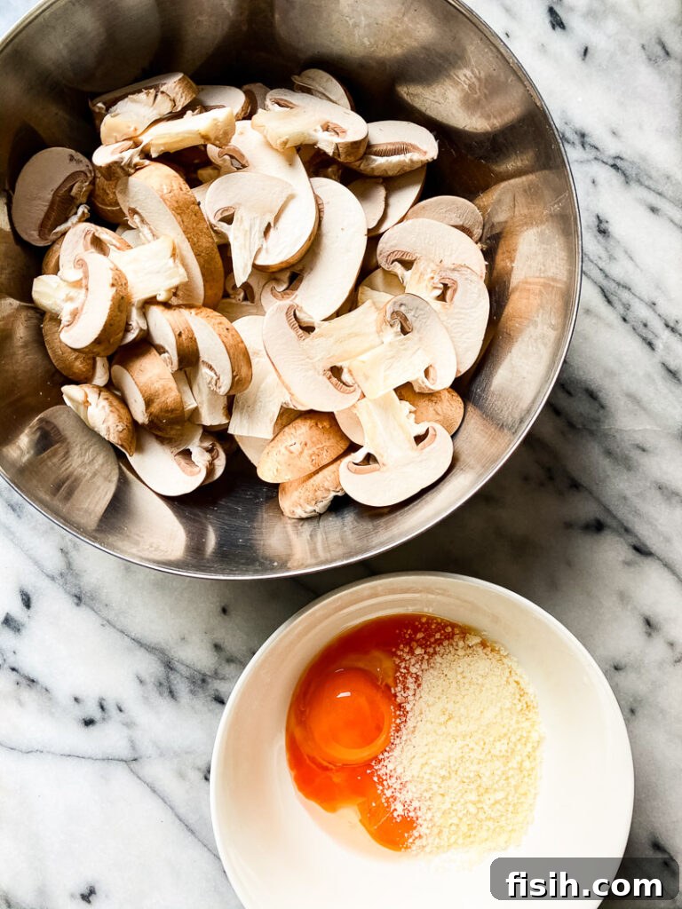 Plant-Based Mushroom Carbonara 4 Top down of mushrooms in silver bowl next to bowl with one egg and cheese