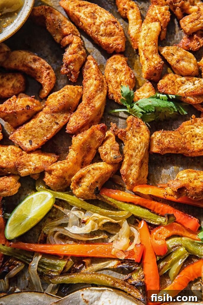 Close up of cooked chicken and bell peppers with lime and cilantro before fajita assembly
