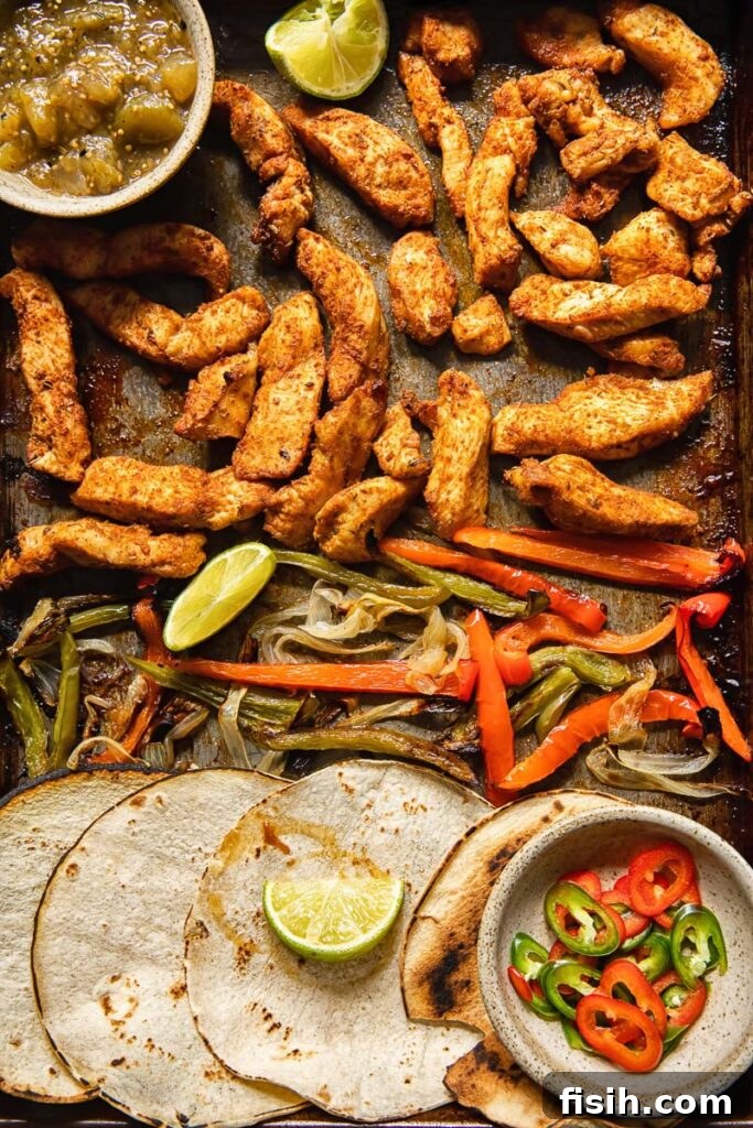 Top down view of tortillas and fajita toppings on a baking sheet