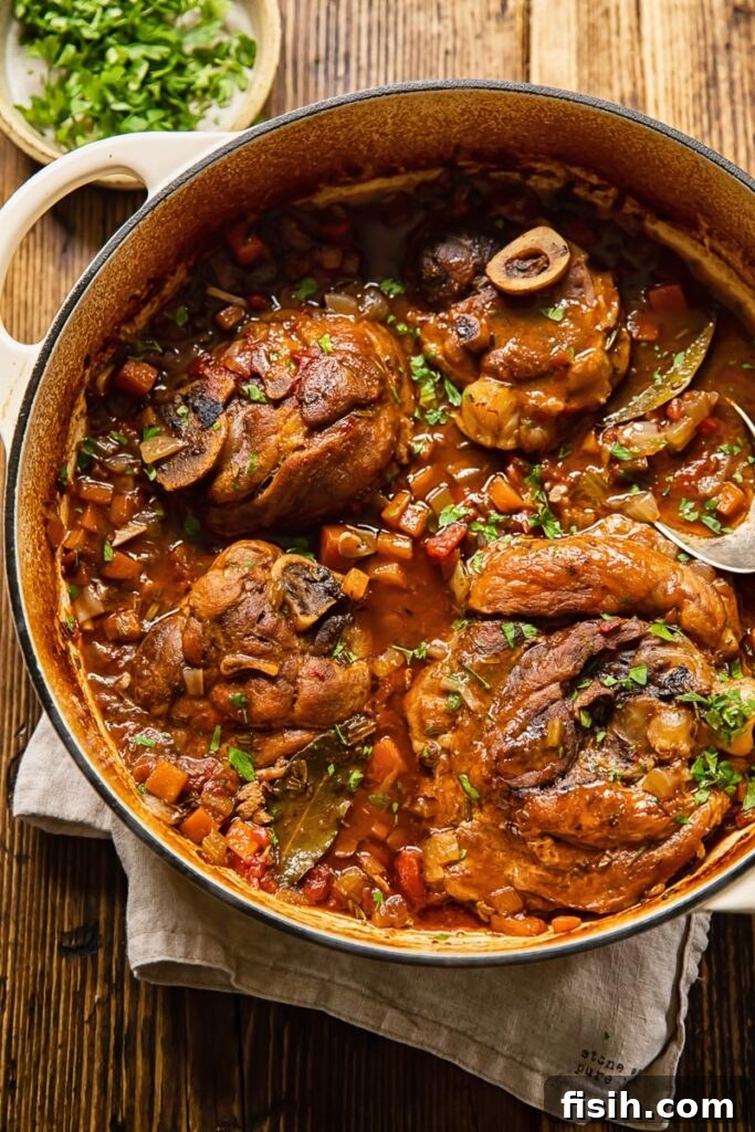 Pork osso buco in a pot with cut up carrots and celery, ready for braising.