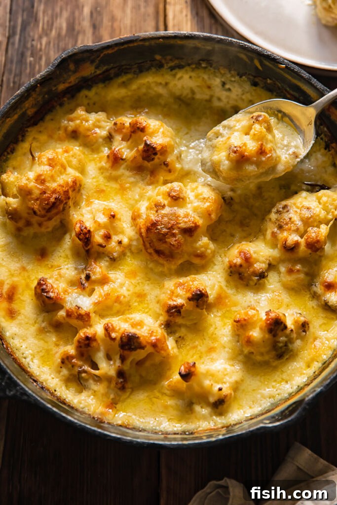 Top down view of spoon taking a bite of cauliflower gratin for cast iron pan