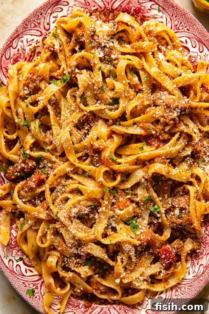 Plate of pasta generously coated with mushroom bolognese, garnished with herbs and cheese.