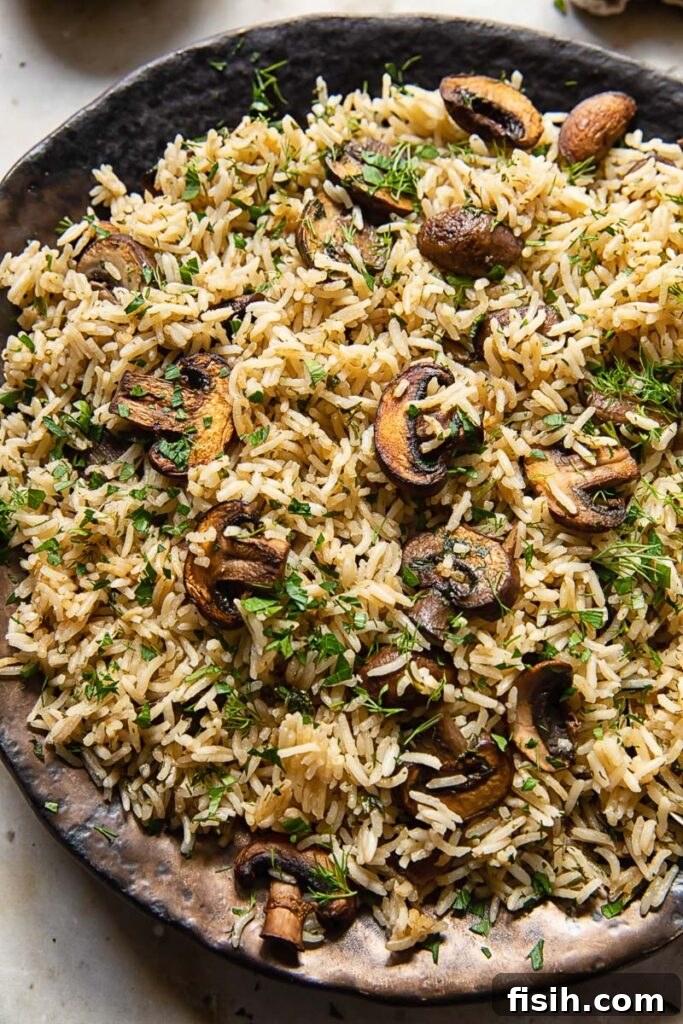 Earthy Mushroom Herb Pilaf 3 Close up view of herbed mushroom rice served on a white plate, garnished generously with fresh parsley and dill, highlighting its vibrant colors and texture.