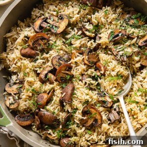 Top down view of mushroom rice in a pot topped with fresh parsley