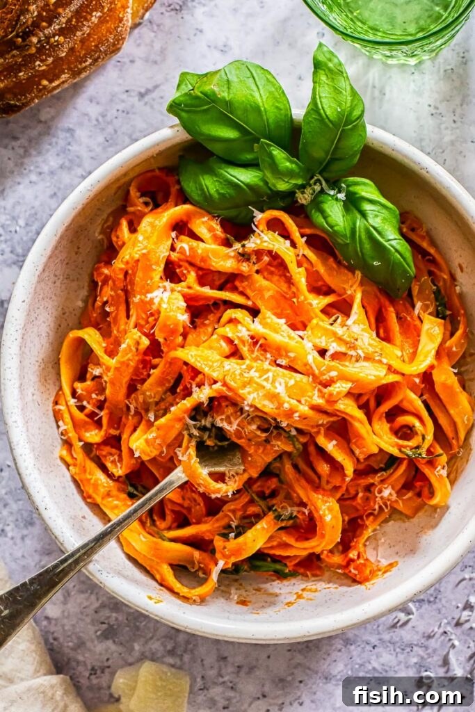 Top down view of a generous bowl of creamy tomato and mascarpone pasta, garnished with fresh basil leaves.